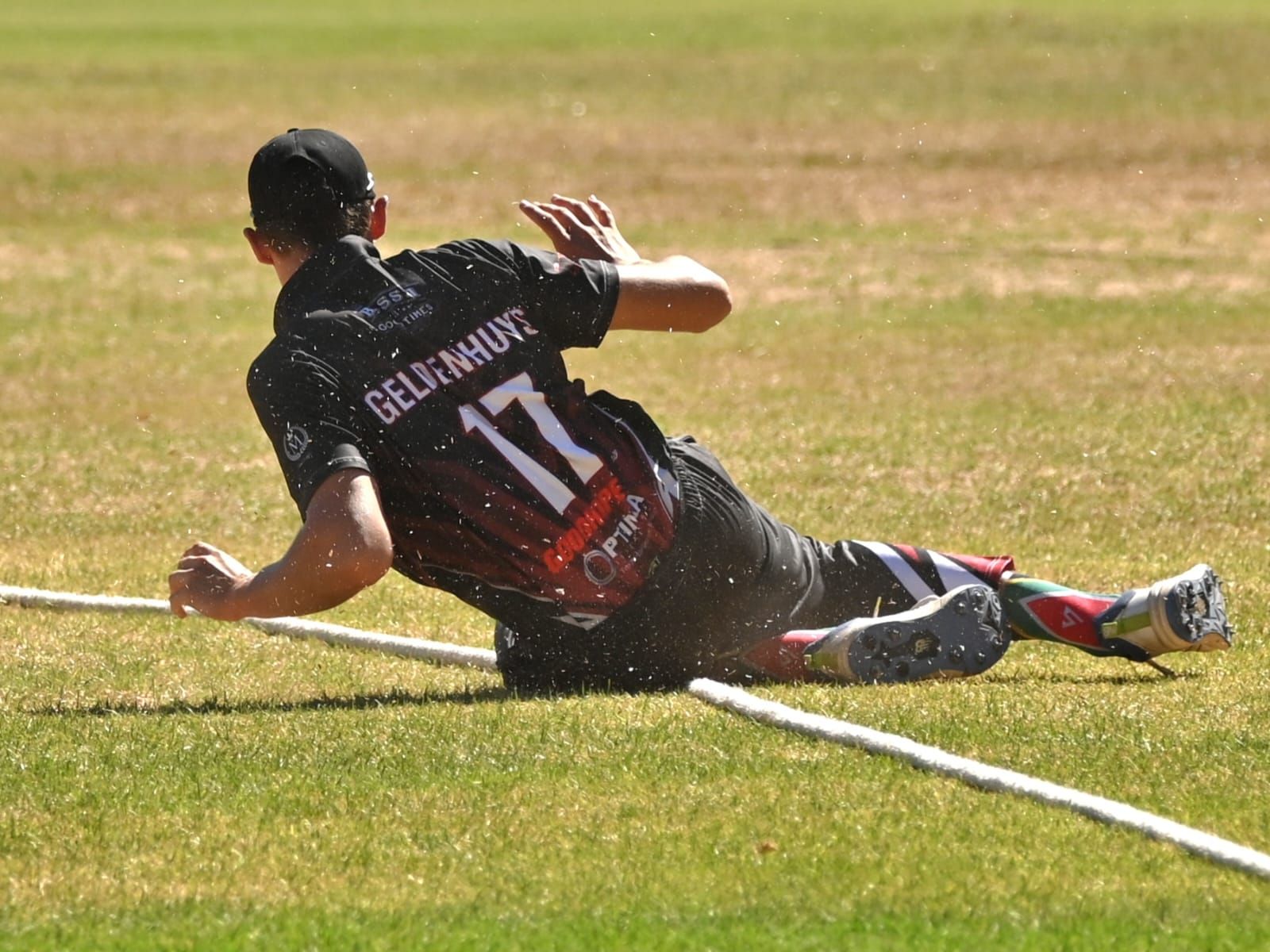Matthew Geldenhuys sliding to stop the ball at the boundary rope, number 17 on his back